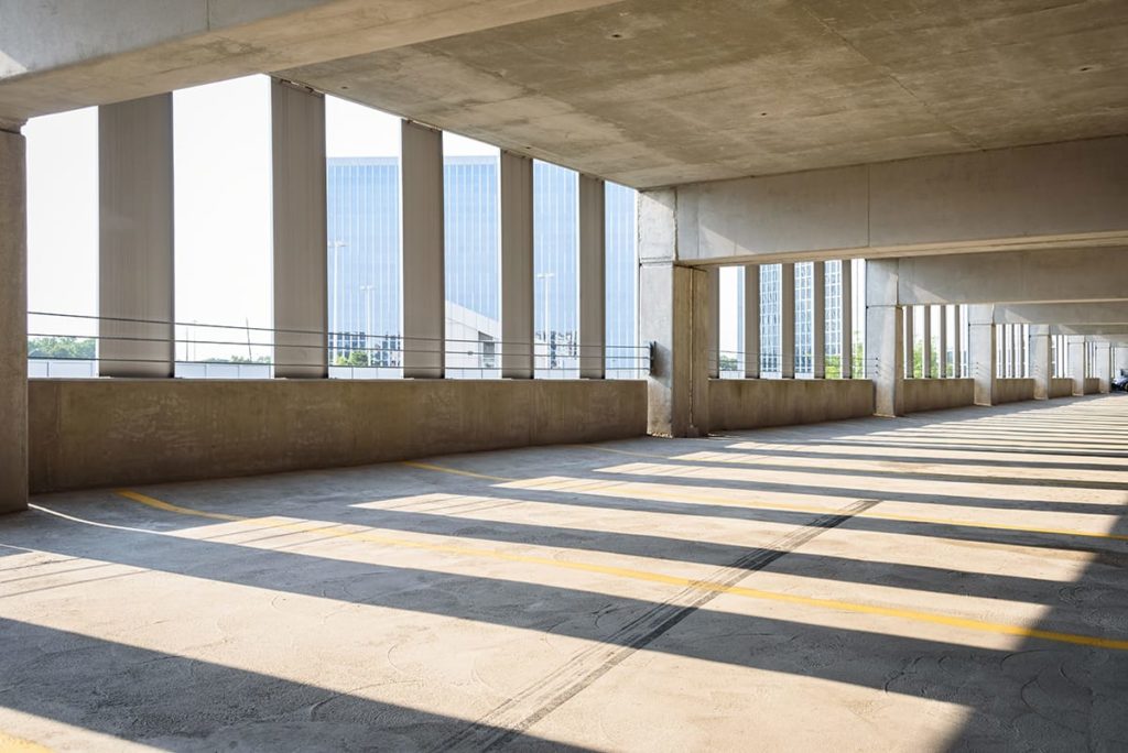 Parking garages use a special traffic coating to secure its flooring and roadways. An upper floor of a parking garage during the daytime.