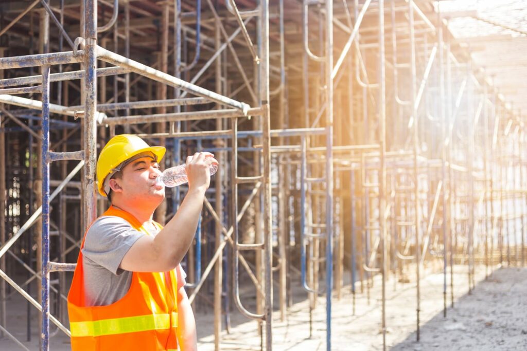 A construction worker takes a water break after pouring concrete in hot weather.