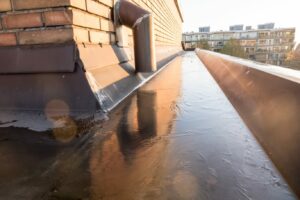Waterproofing Commercial Buildings is imperative for the longevity of rooftops. Water pools after a storm on a rooftop, secured with a waterproofing foundation.
