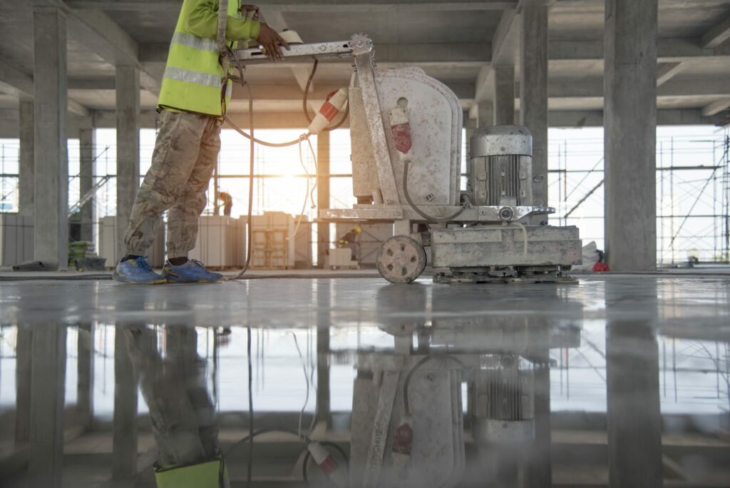 Polished concrete. A construction worker moves a mchine over finished concrete to polish the floor level.