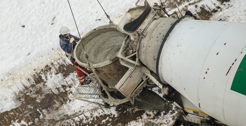 Cold weather concrete mixer about to pour fresh concrete into a tower crane bucket.