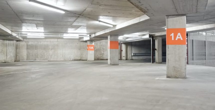 A well lit concrete parking lot with orange floor markers.