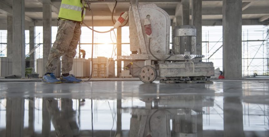 Polished concrete. A construction worker moves a mchine over finished concrete to polish the floor level.