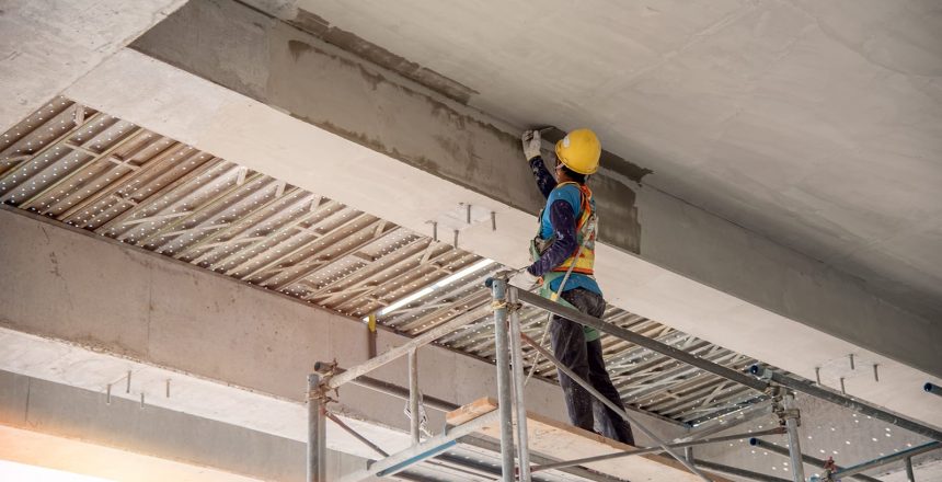 A concrete repair technician seals the underside of a concrete layer of parking ramp.